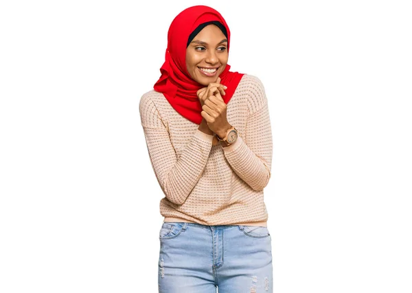 若いですアフリカ系アメリカ人女性身に着けています伝統的なイスラムヒジャーブスカーフ笑い神経と興奮で手であご側を見て — ストック写真