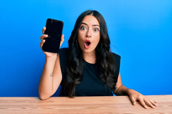 Beautiful Brunette Young Woman Holding Smartphone Showing Blank Screen Scared — Stock Photo, Image