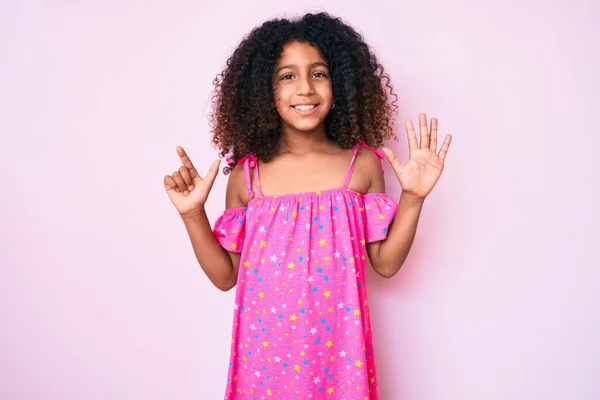 自信と幸せ笑顔ながら カジュアルなドレスを着て 指の番号7で指差す巻き毛のアフリカ系アメリカ人の子供 — ストック写真