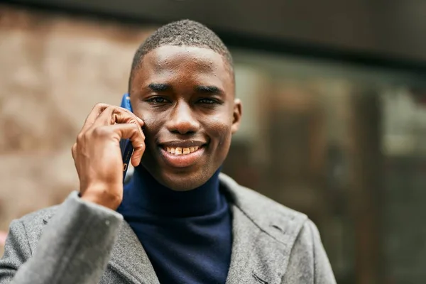 Young african american man smiling happy talking on the smartphone at the city