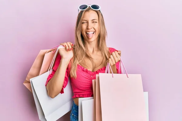 美しいですCaucasian女性保持ショッピングバッグステッキング舌アウト幸せとともに面白い式 — ストック写真