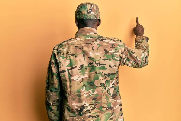 Mladý Africký Američan Nosí Armádní Uniformu Pózovat Pozpátku Ukazuje Dopředu — Stock fotografie
