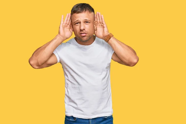 Bonito Homem Musculoso Vestindo Camiseta Branca Casual Tentando Ouvir Ambas — Fotografia de Stock