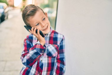 Sevimli beyaz çocuk gülümsüyor. Şehirdeki akıllı telefondan konuşuyor..