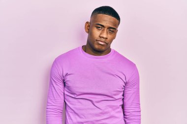 Genç siyah adam rahat pembe süveter giyiyor. Uykulu ve yorgun görünüyor. Yorgunluktan bitkin düşmüş ve akşamdan kalma.. 