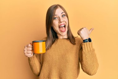 Kafkasyalı güzel bir kadın kahve içiyor başparmağıyla yan tarafa bakıyor ve ağzı açık gülümsüyor. 