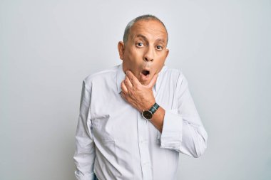 Yakışıklı, beyaz gömlek giyen, inançsızlıktan, şaşkınlıktan ve elleri çenesinde olan şaşaalı yüz ifadesinden büyülenmiş görünen biri. 