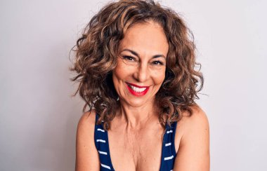 Orta yaşlı, esmer, çizgili tişört giyen, beyaz arka planda duran, kollarını kavuşturup kameraya bakan güzel bir kadın. Pozitif kişi.