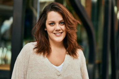 Genç İrlandalı artı cüsseli kız gülümseyerek şehirde mutlu mesut duruyor..