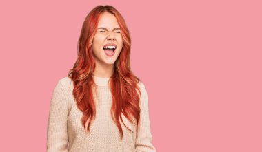 Genç, kızıl saçlı, sıradan bir kazak giyen öfkeli ve öfkeli bir çığlık atan öfkeli bir kadın. Öfkeyle bağırıyor. öfke ve agresif konsept. 