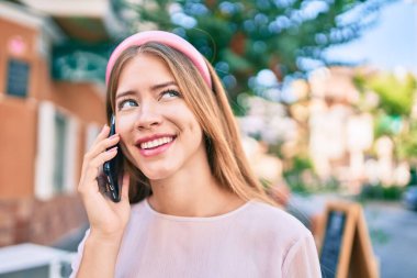 Beyaz kız gülümsüyor. Şehirdeki akıllı telefondan konuşuyor..