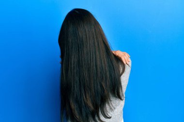 Latin kökenli genç bir kadın gündelik giysiler giyip kendine sarılıyor. Mutlu ve pozitif bir şekilde. Sevgi ve özgüven. 