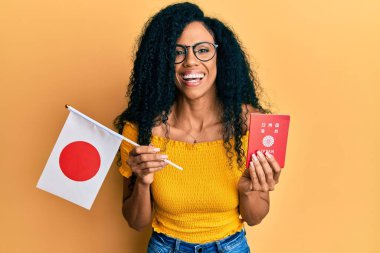Orta yaşlı Afro-Amerikalı kadın elinde Japon bayrağı ve pasaportuyla kahkahalarla gülüyor.. 