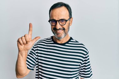 Orta yaşlı İspanyol bir adam gündelik kıyafetler ve gözlük takıyor. Bir fikir veya soruyla gülümsüyor. Mutlu bir yüzle işaret ediyor. 