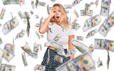 Sıradan beyaz t-shirt giyen genç sarışın kız şaşırmış yüz ifadesiyle şok olmuş, parmaklarından bakan gözler. İnançsız ifade.