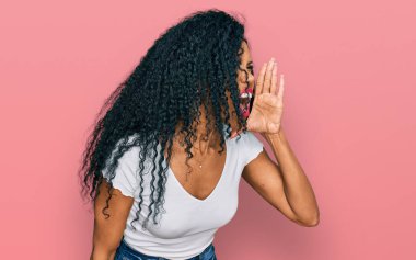 Orta yaşlı Afro-Amerikalı kadın günlük beyaz tişört giyip el ele tutuşarak bağırıyor ve çığlık atıyordu. iletişim konsepti. 