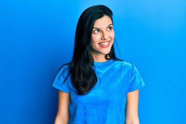 Latin kökenli genç bir kadın günlük giysiler giyiyor. Tarafını arıyor, profil pozu veriyor. Doğal bir yüzü ve kendine güvenen bir gülümsemesi var.. 