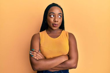 Kollarını kavuşturmuş genç Afrikalı Amerikalı kadın gülümsüyor ve başka tarafa bakıyor.. 