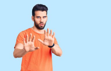 Sakallı, gündelik tişörtlü genç yakışıklı. Avuçlarını hareket ettiriyor. Korkmuş ve iğrenç bir ifadeyle reddediyor. Dur ve yasakla. 