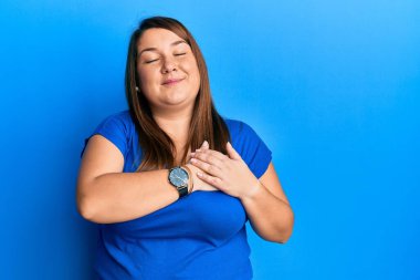 Güzel esmer, iri yarı, sıradan mavi tişört giyen, elleri göğsünde, gözleri kapalı ve yüzünde minnet ifadesi olan bir kadın. sağlık kavramı. 