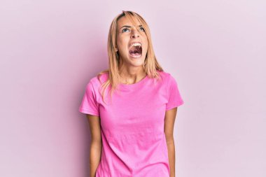 Güzel, pembe bir tişört giyen, sinirli, sinirli, sinirli, öfkeli ve öfkeyle bağıran güzel bir kadın. öfke ve agresif konsept. 