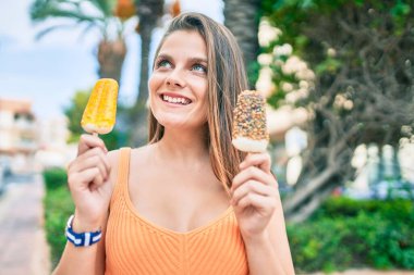 Genç ortadoğu kızı gülümseyerek şehirde dondurma yiyor..