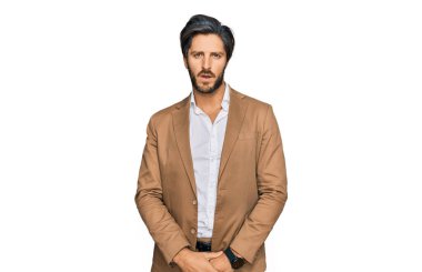 Şok olmuş, iş kıyafetleri giymiş genç İspanyol bir adam şüpheci ve alaycı görünüyor, ağzı açık kalınca şaşırıyor. 