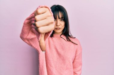 Kâküllü, kışlık süveter giyen genç esmer kadın mutsuz ve sinirli görünüyor. Reddedilmiş ve olumsuz jestler yapıyor. kötü ifade. 