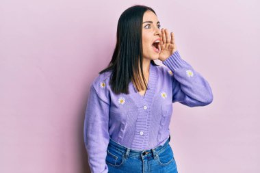 Çiçek desenli bahar hırkası giyen genç esmer kadın el ve ağızla bağırarak ve yüksek sesle bağırıyor. iletişim konsepti. 