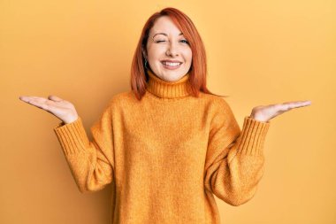 Güzel kızıl saçlı kadın, avucu açık bir şekilde kameraya bakıyor. Seksi bir ifadeyle, neşeli ve mutlu bir yüzle.. 