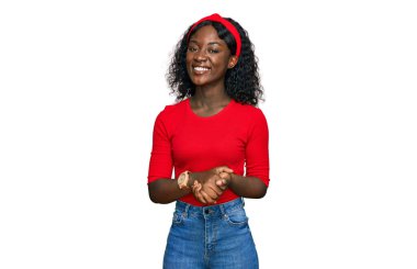 Güzel Afrikalı genç bir kadın, günlük kıyafetler giyip ellerini birleştirip gülümseyerek gevşemiş ve neşeliydi. Başarı ve iyimserlik 