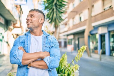Genç beyaz adam gülümseyerek şehirde mutlu mesut yürüyor..