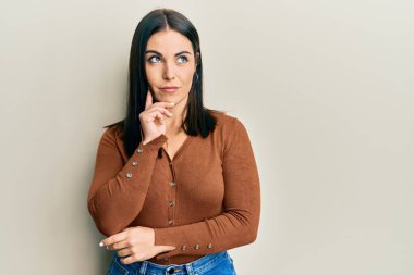 Genç esmer kadın gündelik kıyafetler giyiyordu. Kuşkuya yoğunlaşmıştı. Parmakları çenesinde ve yukarı bakıyordu. 