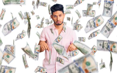 Yakışıklı Latin Amerikalı rahat bir yaz tişörtü giymiş üzgün ve üzgün görünüyor, parmaklarıyla yönü gösteriyor, mutsuz ve depresif..