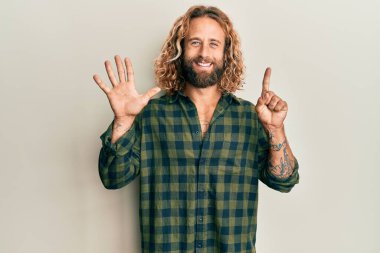 Sakallı, uzun saçlı, sıradan kıyafetler giyen, altı numaralı parmaklarıyla işaret eden, kendinden emin ve mutlu bir adam.. 