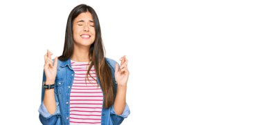 Genç esmer kadın, günlük kıyafetler giyip umut ve gözlerin kapalı gülümseyerek el sallıyor. Şans ve batıl inançlar. 