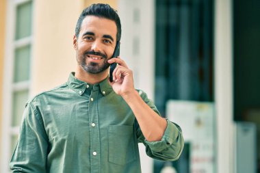 Genç İspanyol adam gülümsüyor. Şehirdeki akıllı telefondan konuşuyor..