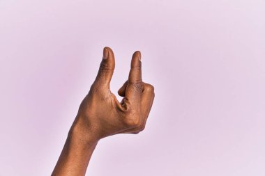 Siyah orta yaşlı bir kadının kolu ve eli pembe izole edilmiş arka plan üzerinde. Görünmez bir şeyi alıp götürüyor. Parmaklarıyla uzayı gösteren bir nesneyi tutuyor. 