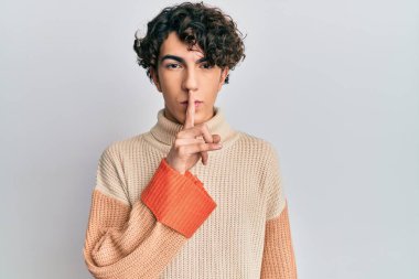 Sıradan bir kazak giyen İspanyol genç adam parmakları dudaklarında sessiz olmak istiyor. sessizlik ve gizli konsept. 