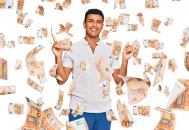 Gündelik giysiler giyen genç Arap adam farklı yönleri gösteren kendine güvenle gülümsüyor. reklam için kopyalama alanı