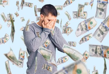 Genç ve yakışıklı bir adam, ağlarken suratını ellerle kapatan sıradan bir kazak giyiyor. depresyon kavramı.