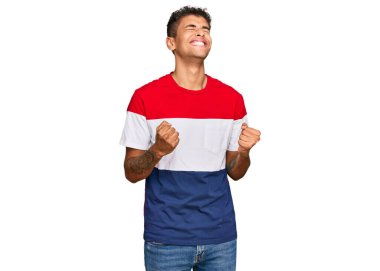 Genç, yakışıklı, Afro-Amerikalı, sıradan kıyafetler giyen, başarılı olmak için heyecanlanan, kolları havada, gözleri kapalı, zaferi kutlayan, gülümseyen bir adam. Kazanan konsept. 