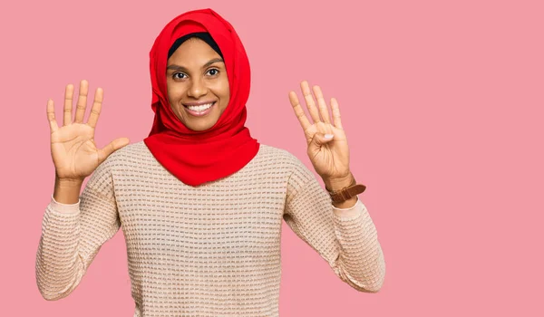 自信と幸せ笑顔ながら 伝統的なイスラムヒジャーブスカーフを身に着けている若いアフリカ系アメリカ人の女性は 指の数9で示すと指摘します — ストック写真