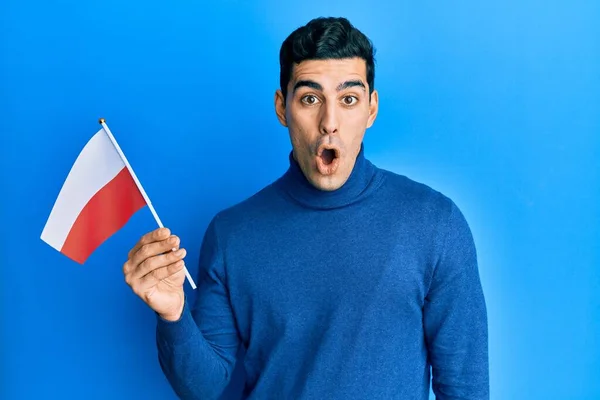 Красивый Латиноамериканец Держащий Флаг Польши Испуганный Изумленный Открытым Ртом Удивления — стоковое фото