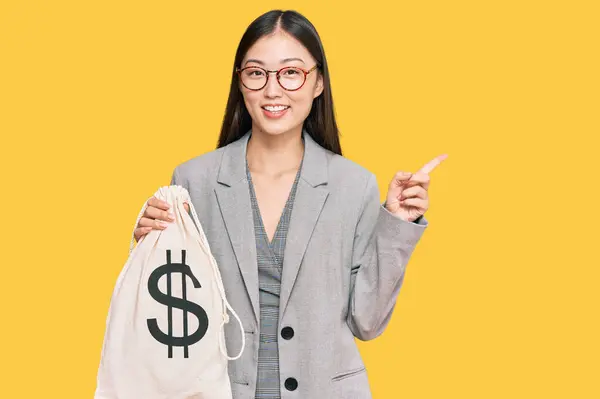Jovem Chinesa Vestindo Terno Negócios Segurando Saco Dólares Sorrindo Feliz — Fotografia de Stock