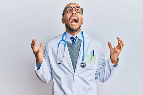 医師の制服を着たヒスパニック系の大人の男と狂気と怒鳴り声と積極的な表現と腕を上げて叫んで聴診器 フラストレーションコンセプト — ストック写真