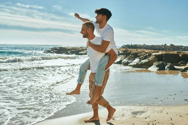 可爱的一对同性恋夫妇骑在沙滩上 — 图库照片