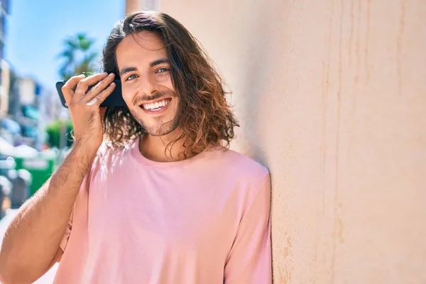 Joven Hombre Hispano Sonriendo Feliz Hablando Smartphone Apoyado Pared —  Fotos de Stock