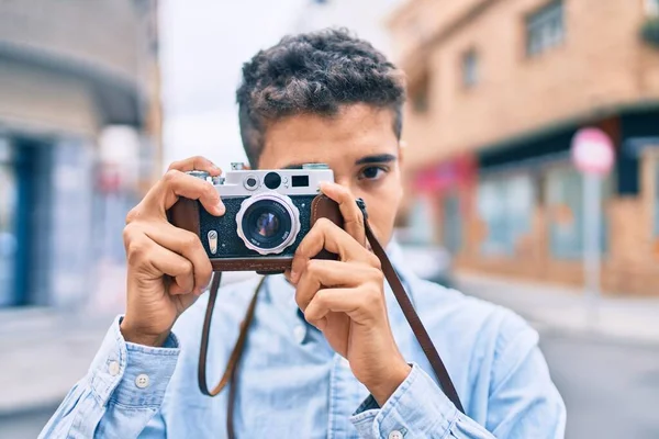 若いですラテン観光の男笑顔幸せな使用してヴィンテージカメラ歩行で街 — ストック写真