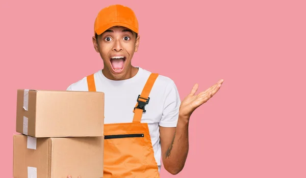 Young Handsome African American Man Holding Delivery Package Celebrating Victory — Stok fotoğraf